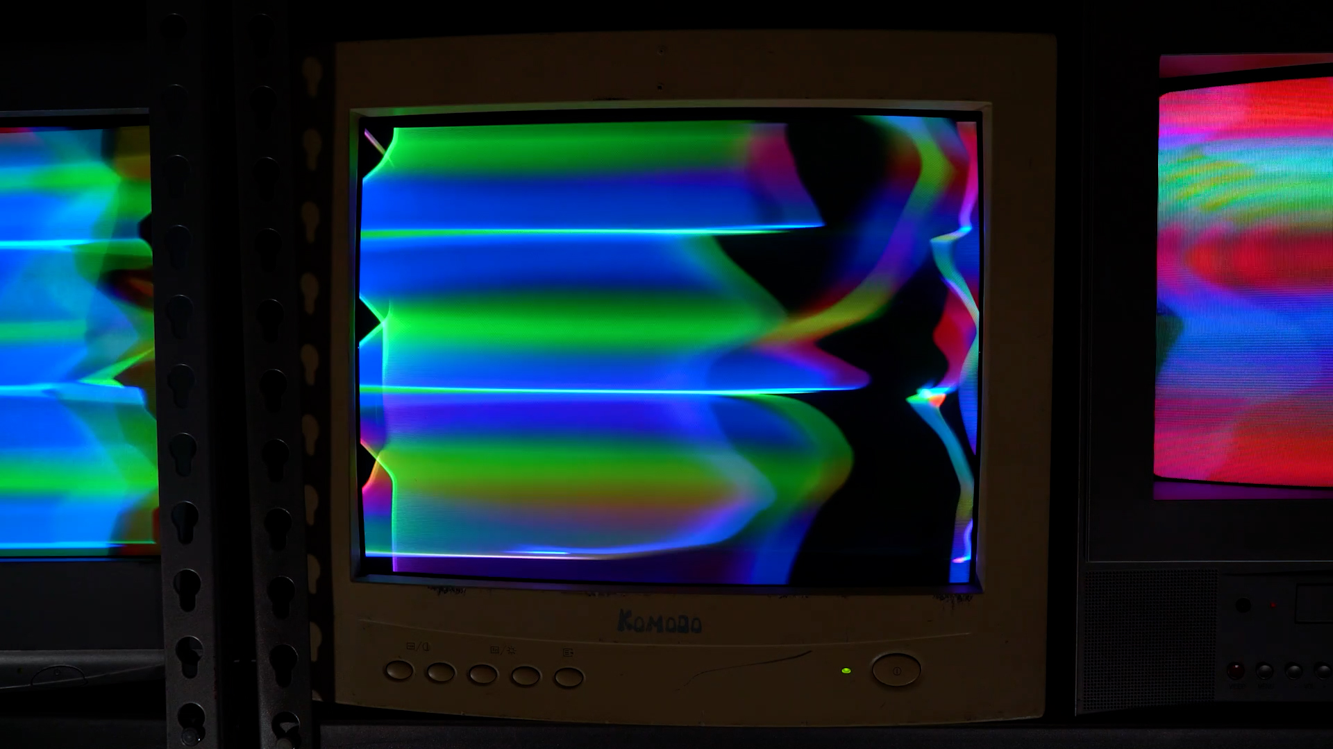 Closeup of a CRT monitor showing bright video synthesis colors glitched by electromagnetic signal