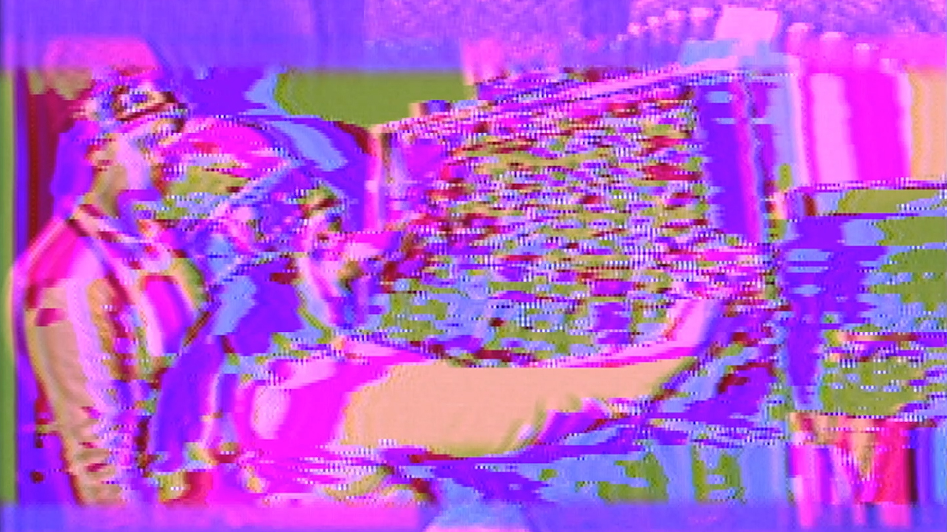 James Connolly and Monica Panzarino performing the Sandin Image Processor, processed on the Sandin Image Processor to appear pink, purple, green, and blue with broken imagery.
