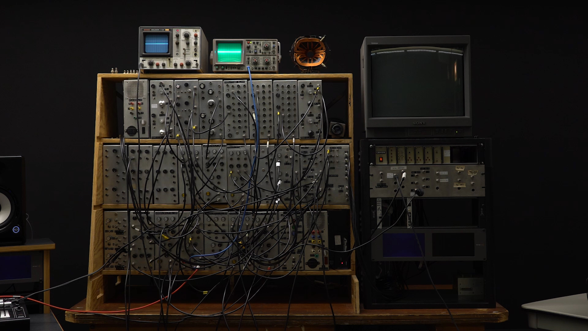 Image of the Sandin Image Processor—a stack of several metal boxes with knobs and input/output jacks with patch cables attached to them.