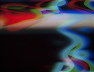 Visuals generated with the RGB.VGA.VOLT video synthesizer; reds, cyans, blues, and whites swirl across the top and right of a mostly black screen.